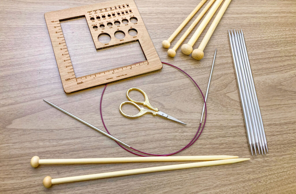 Different types of knitting needles on a table: straight, circular and double pointed needles